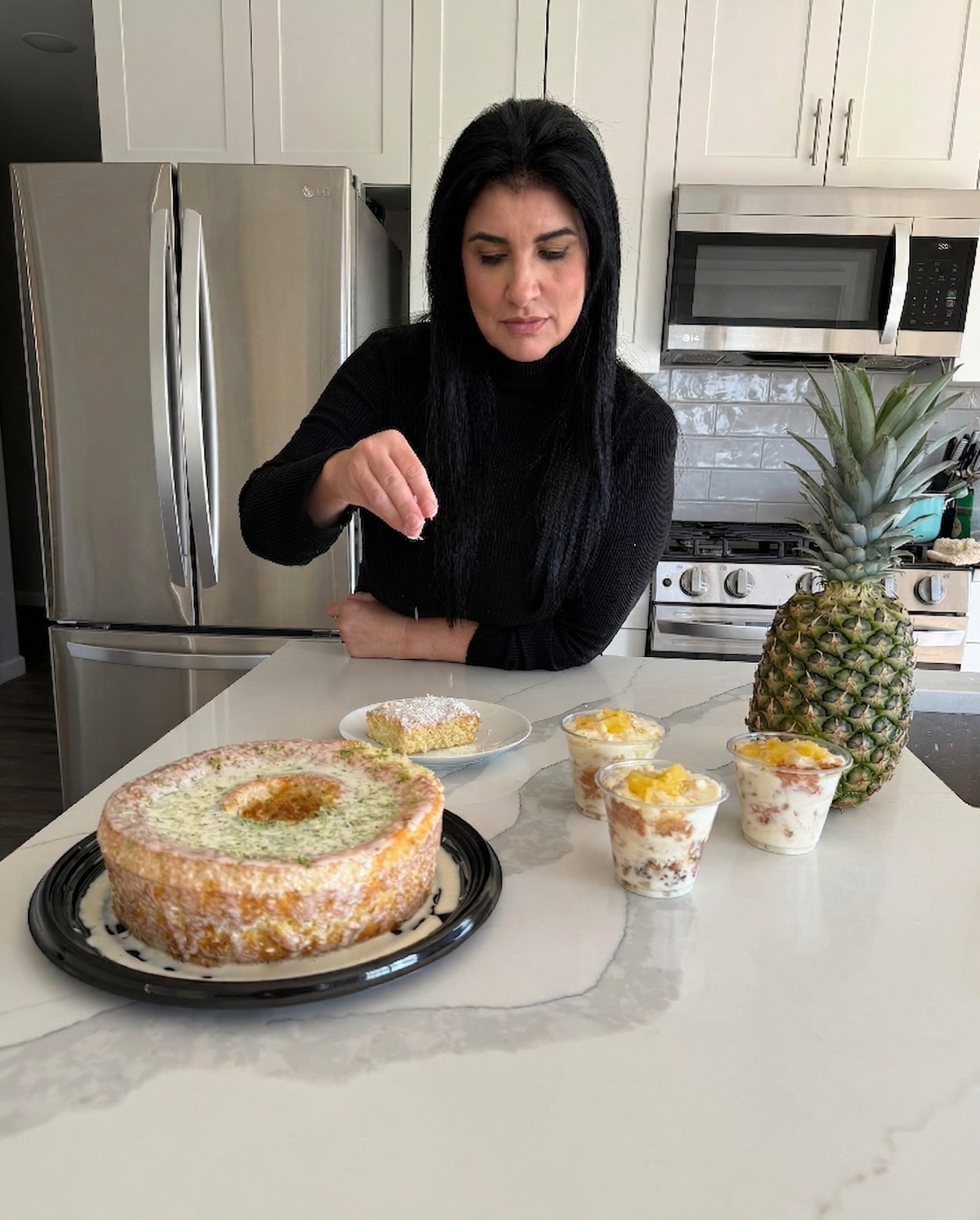 Lala preparing homemade dishes in a bright kitchen, with sweet treats and savory plates laid out on the counter